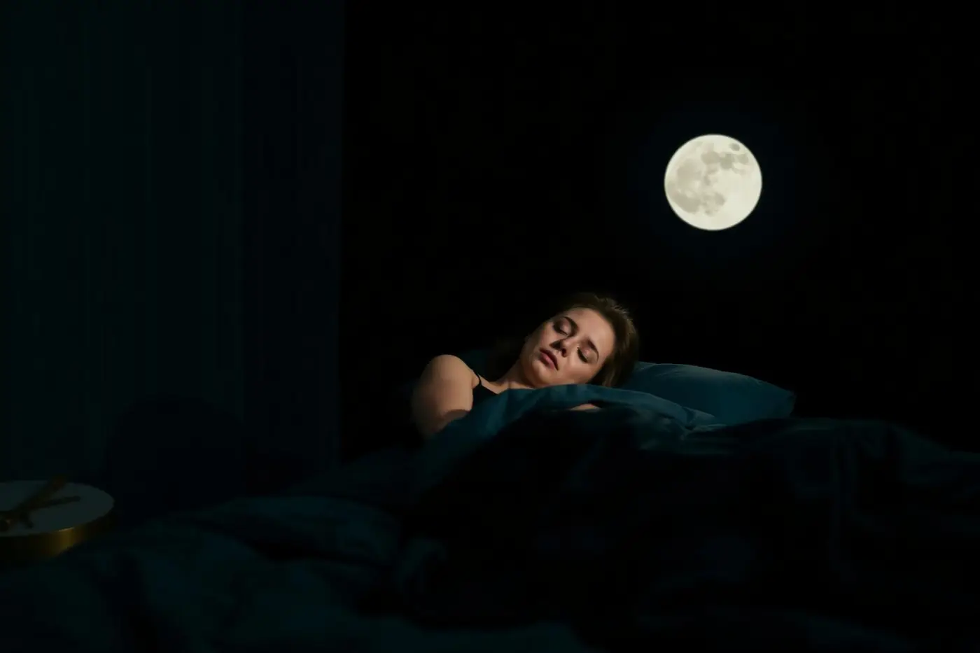 Person sleeping in a dark, calm bedroom under moonlight